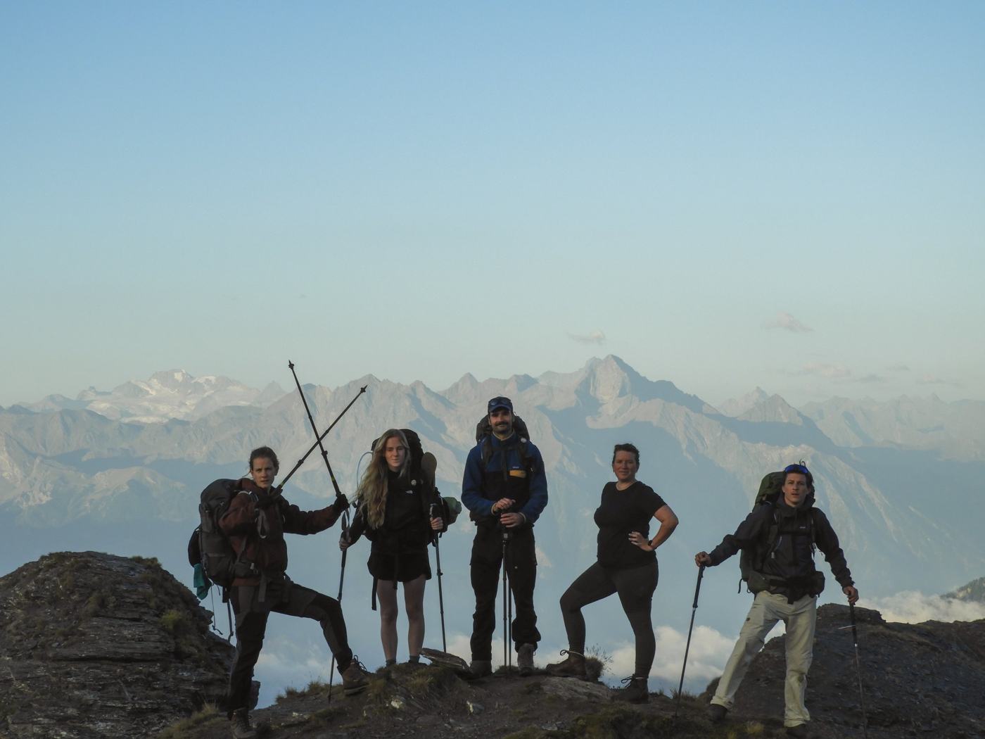 Groep wandelaars poseert op een bergkam boven de wolken in de Aostavallei
