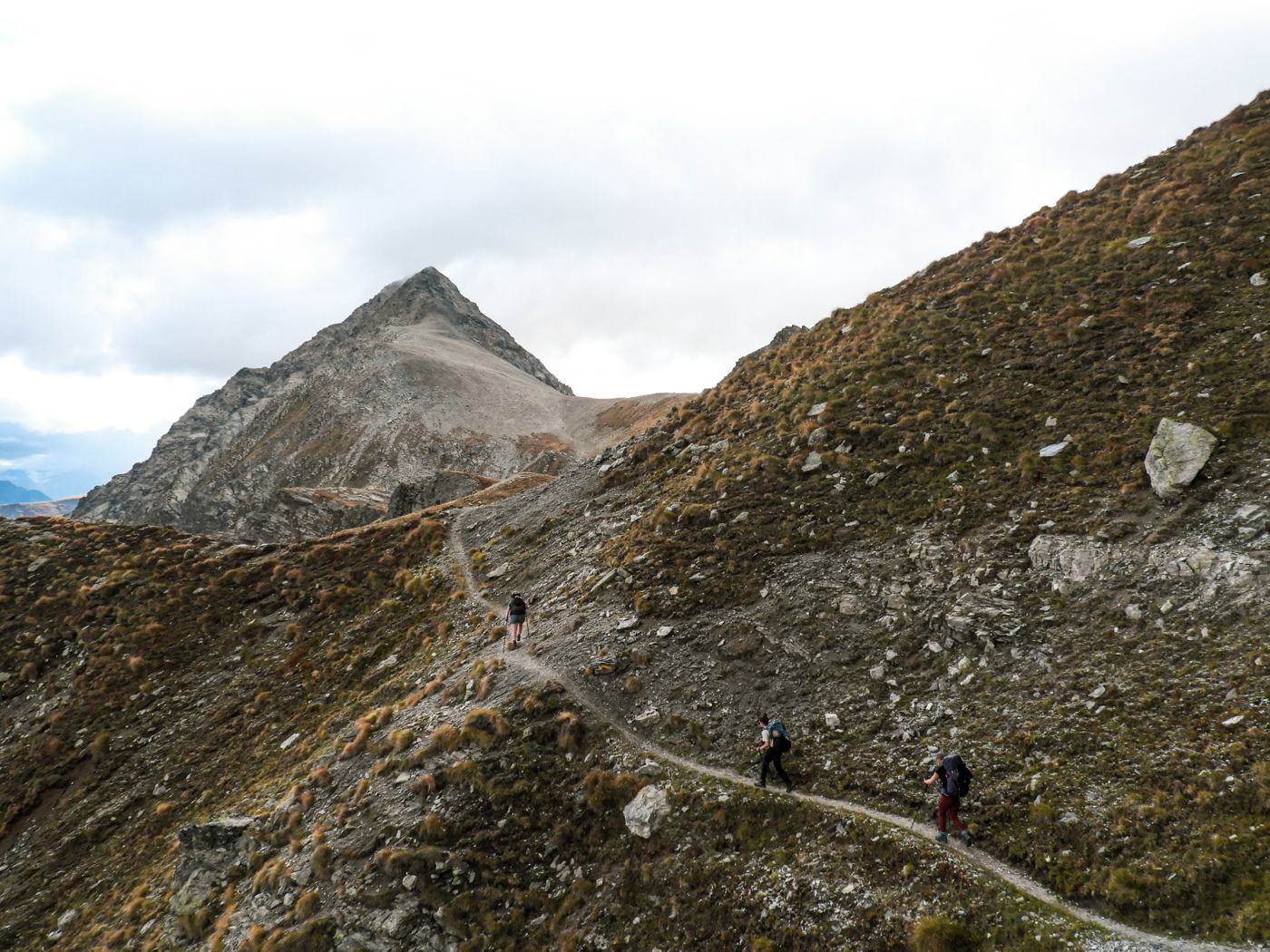 Wandelaars op een smal bergpad richting een piramidevormige top