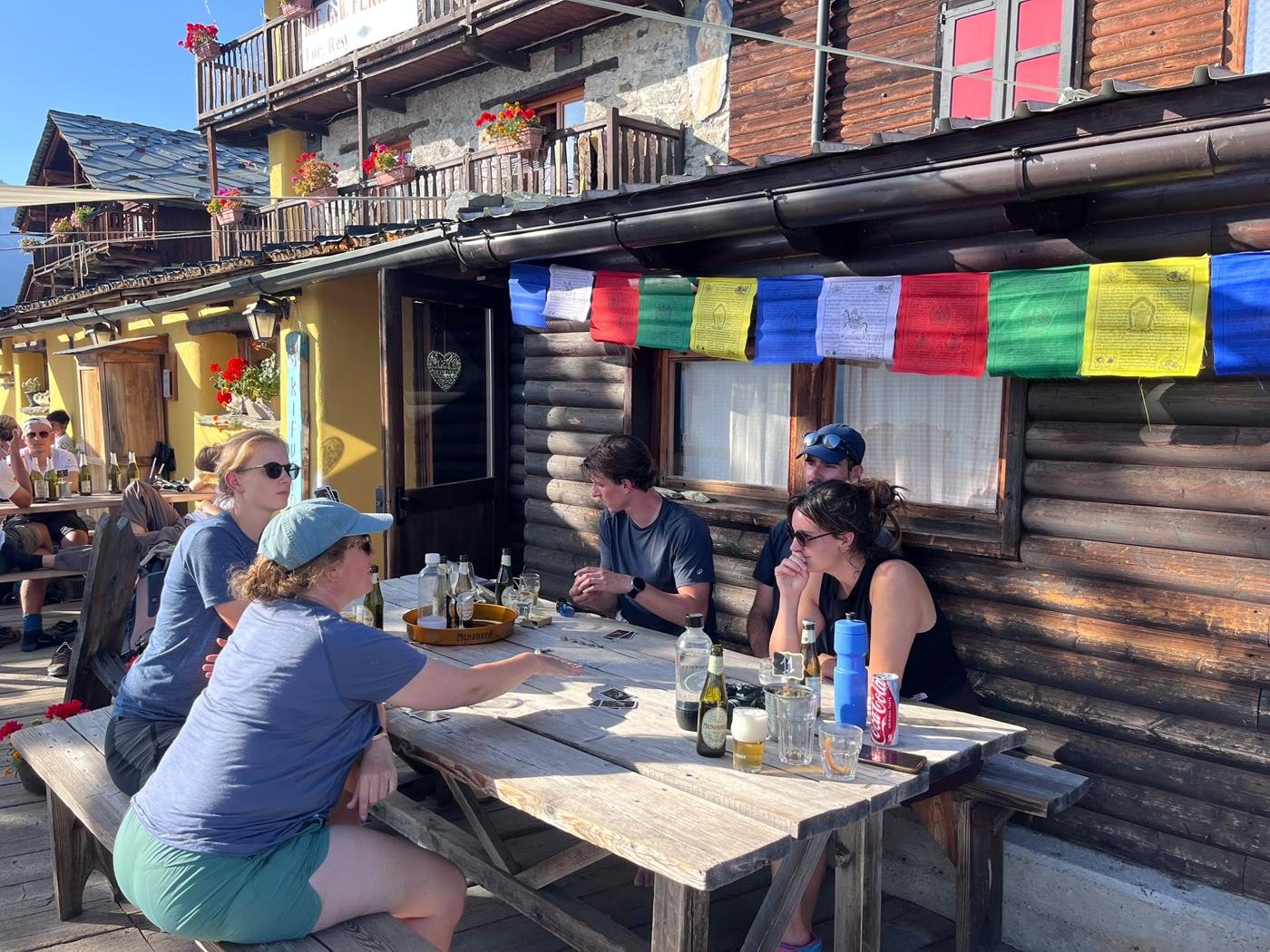 De groep speelt kaart met een drankje op het zonnige terras van een berghut