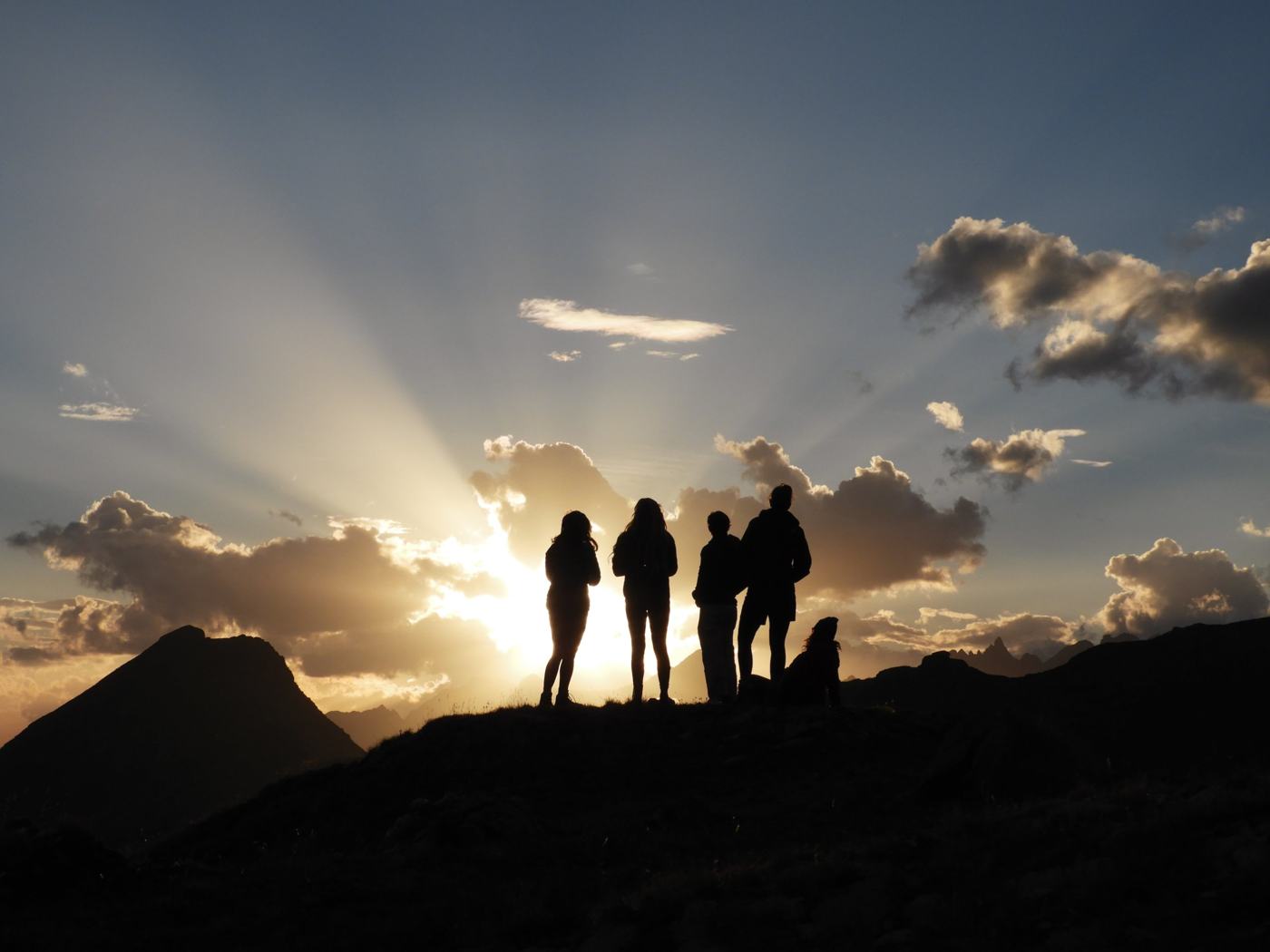Silhouetten van de groep tegen een zonsondergang in de bergen