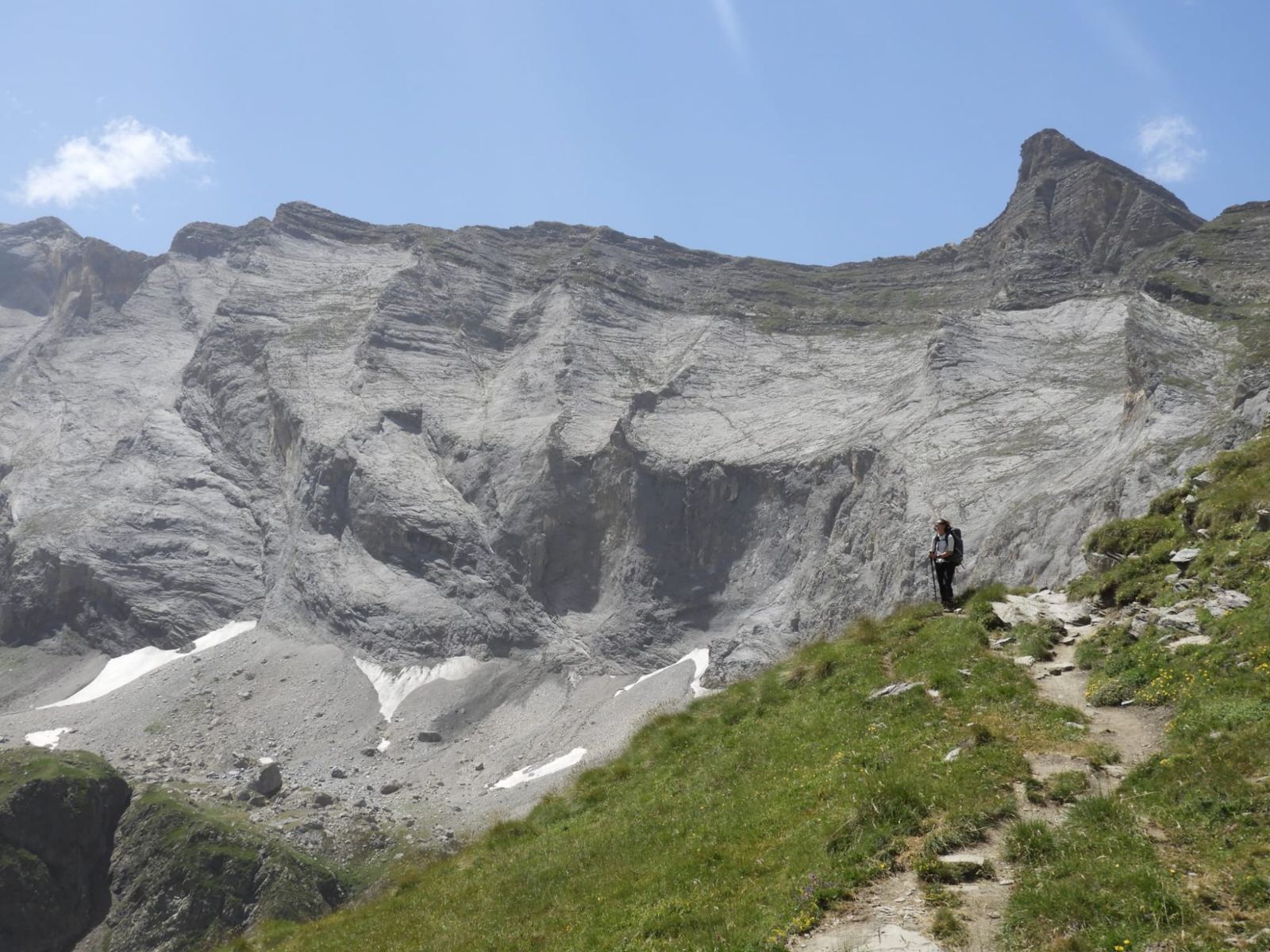 Wandelaar op een bergpad onder een grote rotswand