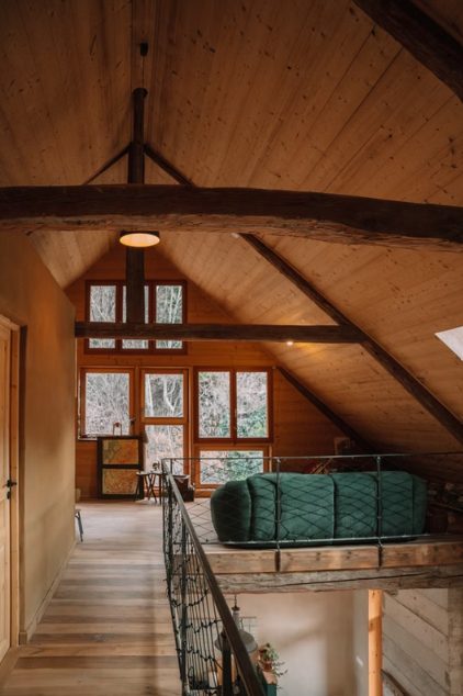 Houten mezzanine met groene zetel onder het dak van de gîte