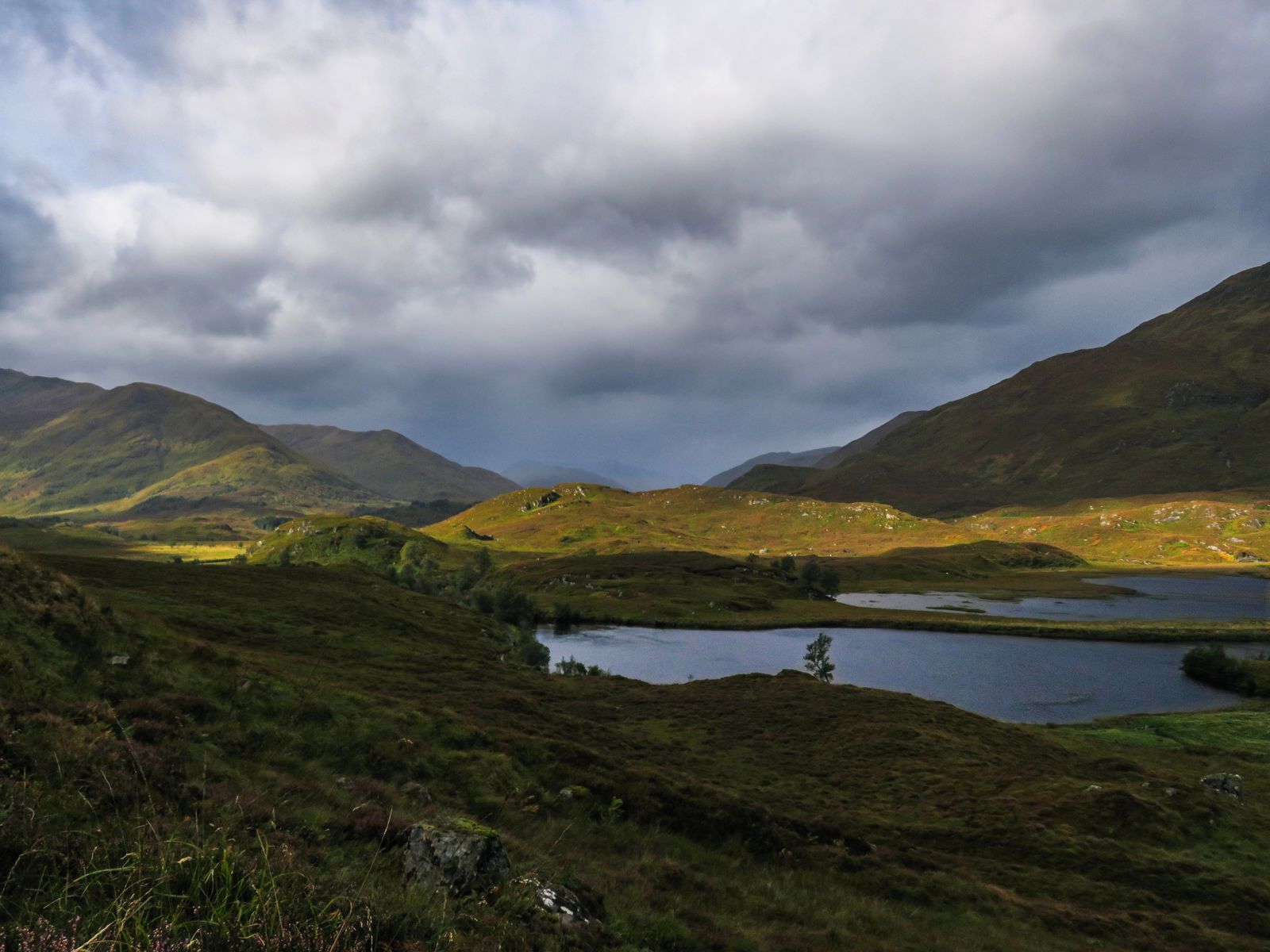Brede vallei met lochs onder dreigende wolken in de Schotse Highlands